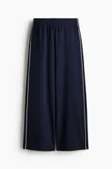 Jogging azul marino de corte holgado, tiro alto con cintura elástica fruncida y cordón oculto. Presenta piernas anchas con bolsillos laterales discretos y un bolsillo trasero abierto.