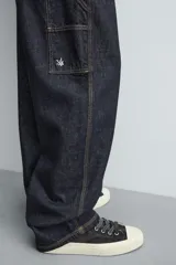 Jeans de hombre relaxed straight fit, color azul oscuro, confeccionados en denim rígido sin prelavados. Presentan cinco bolsillos, bolsillos plastrón y tira multifunción en las perneras. Cierre frontal con cremallera y botón.