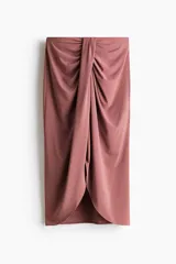Pollera midi de punto suave, color rosado, con cintura elástica de tiro alto y detalle drapeado frontal con abertura asimétrica.