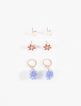 Set de tres pares de caravanas plateadas: un par de aros tipo botón con forma de media luna, un par de aros tipo botón con forma de flor con incrustaciones verdes y un par de aros colgantes con forma de racimo de uvas rojas.