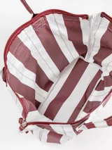 Bolso tipo tote grande, resistente al agua, con diseño de rayas verticales rojas y blancas. Cuenta con asas largas de hombro, cierre superior y parche de cuero con logo grabado. Incluye neceser transparente a juego con base y detalles a rayas.