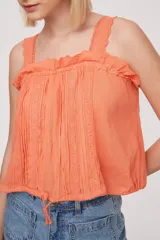 Musculosa blanca con breteles finos y detalles de puntilla.