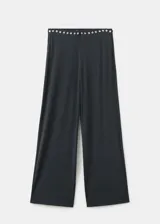 Pantalón largo gris oscuro de tiro medio, con cintura elástica y detalles de tachas metálicas redondas en el borde de la cintura, corte recto y silueta amplia.