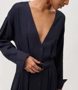 Vestido largo midi estilo chemise de color azul marino, confeccionado en mezcla de viscosa y lino. Presenta escote en V, mangas largas con puños abotonados, cierre frontal de botones y cinturón ajustado del mismo tejido con hebilla redondeada.