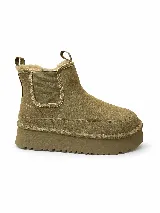 Botas estilo UGG de gamuza color tostado, con plataforma gruesa dentada, elásticos laterales tipo chelsea, interior de corderito sintético y trabillas traseras para facilitar el calce.