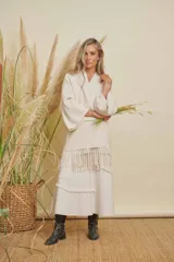 Saco color arena con cuello en V, mangas anchas y diseño holgado. Presenta detalles de flecos en la parte inferior.