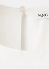 Vestido midi color blanco con diseño evasé, cuello redondo y sin mangas de tirante ancho. Cuenta con un detalle de pañuelo bordado en la cintura con cierre de cremallera lateral.