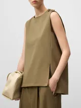 Chaleco sastre de corte recto y diseño minimalista en color verde oliva. Presenta cuello redondo, cierre con dos botones en el hombro izquierdo, sisas amplias y aberturas laterales en el bajo.
