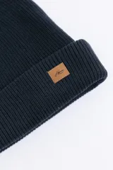Gorro de punto inglés en color azul marino, con diseño de doble capa y etiqueta de cuero sintético con logo en el frente.