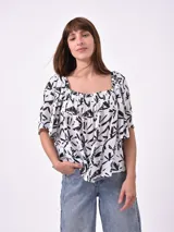 Blusa negra con escote cuadrado, fruncido en el busto y mangas cortas amplias.