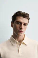 Polo de corte regular fit en tejido de algodón con estructura vertical color beige. Presenta cuello solapa, cierre frontal de botonadura y manga corta con rib.