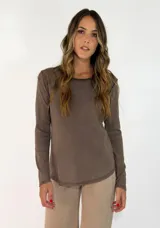 Remera de manga larga en color marrón, con cuello redondo y diseño de corte recto con ruedo ligeramente redondeado.