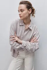 Camisa de viscosa color celeste, de calce amplio y caída fluida, con cuello clásico, cierre frontal de botones y detalles calados en mangas y delantero.