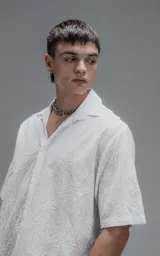 Camisa oversize blanca de manga corta y cuello abierto, confeccionada en algodón con diseño bordado.