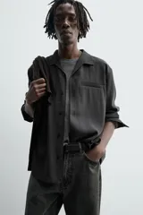 Camisa de manga larga color negro, confeccionada en tejido fluido con mezcla de viscosa. Presenta cuello bowling, bolsillo de vivo en el pecho y efecto lavado.