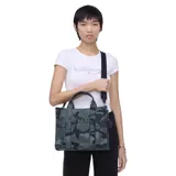 Bolso tote de Marc Jacobs en tejido jacquard con estampado de camuflaje en tonos verdes y negros. Presenta el logo de la marca bordado en relieve en el frente, doble asa superior y correa de hombro ajustable y extraíble.