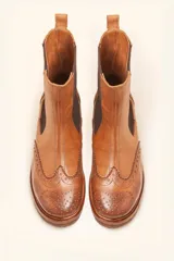 Bota tipo Chelsea de cuero vacuno color suela, con diseño brogue en la puntera y laterales. Presenta paneles elásticos laterales en color marrón oscuro, tirador trasero y suela de goma con plataforma.