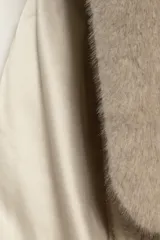 Bufanda de piel sintética color marrón oscuro, con forro interior de satén liso del mismo tono. Presenta un diseño con una abertura central para pasar un extremo y asegurar la bufanda al cuello.