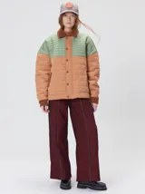 Campera capitonada de gabardina de algodón con diseño en bloques de color verde y tostado. Cuenta con cuello camisero, puños, canesú y bolsillos de pana marrón, cierre frontal oculto con botones y bolsillos laterales.