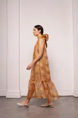 Vestido largo color ocre con estampado de cuadrados dorados, cuello alto y corte amplio. Incluye viso liso al tono.