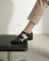 Zapato tipo cangrejera de cuero color marrón oscuro, con diseño de tiras entrelazadas, pulsera con hebilla ajustable al tobillo y taco bajo de madera.