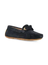 Mocasín de gamuza color azul marino, con detalle de aplique metálico dorado en el empeine y suela de goma marrón.