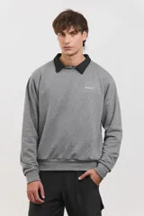 Buzo de algodón rústico color gris melange, con cuello redondo y cuello tipo polo negro superpuesto. Presenta el logo de la marca bordado en el pecho y puños acanalados.