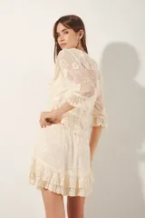 Blusa de encaje color crema con bordados florales, escote en V profundo con volados y mangas 3/4 terminadas en volantes. Diseño de estilo romántico con transparencias y cintura elástica.