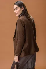 Blazer de corte clásico y estructurado en color marrón con textura de espiga. Presenta solapas tradicionales, cierre frontal y mangas largas.