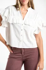 Blusa blanca de algodón con cuello mao, cierre frontal de botones y volados en los hombros con detalle de bordado inglés.