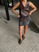 Faja ancha de cuero marrón con diseño cruzado, decorada con tachas metálicas en todo su contorno y cierre mediante hebilla de argolla metálica.