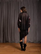 Camisa de manga larga con diseño de terciopelo estampado con motivos florales y paisley, combinada con paneles de tela transparente en la parte superior. Presenta cuello clásico, cierre frontal con botones y mangas abullonadas.