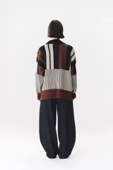 Buzo de tejido de punto con diseño de bloques de rayas verticales en colores rojo, verde, bordó y crema. Presenta cuello alto, corte oversize y terminaciones en rib en puños y ruedo.