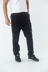 Pantalón cargo de corte slim, color negro, con bolsillos laterales con solapa y botones metálicos. Cuenta con cierre frontal, botón en la cintura y pasacintos.