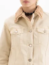 Campera tipo trucker de denim color crudo, con cierre frontal de botones metálicos, bolsillos frontales con solapa y cuello con forro de simil corderito.