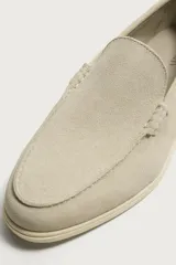 Mocasín casual de hombre confeccionado en piel con acabado serraje en color beige, con detalle de bordón en el empeine y suela fina al tono.
