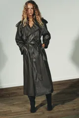 Trench coat de Zara con efecto piel texturizada en color gris oscuro. Presenta cuello con solapas, cierre frontal cruzado con botones, cinturón lazada del mismo material, mangas largas con trabillas y abertura en la espalda.
