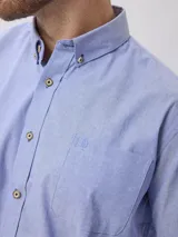 Camisa de corte clásico confeccionada en tejido Oxford de algodón, con cuello abotonado, manga larga y bolsillo frontal en el pecho.