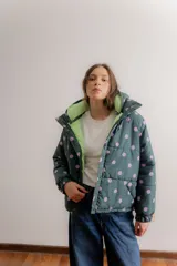 Campera puffer con capucha desmontable, color verde oscuro con estampado de lunares lilas. Cuenta con cierre frontal, bolsillos laterales y forro interno en color verde claro.