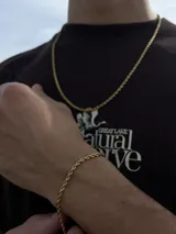 Conjunto de joyería compuesto por una cadena tipo soga y una pulsera a juego, ambos en color dorado.