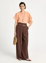 Pantalón sastrero marrón de pierna ancha, tiro alto, pretina estructurada con trabillas, pliegues frontales y cierre de cremallera.