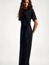 Vestido largo negro de manga corta, con cuello redondo y detalle de nudo o lazo ajustable en la cintura.