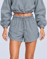 Short gris con cintura tipo clochard con regulador, ajustes con cordón en los laterales y bolsillos. Confeccionado en tejido ultra suave de poliéster y poliamida con protección UV 50+.
