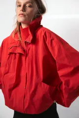 Chaleco de punto sin mangas, color rojo, con cuello subido y diseño de tejido texturizado.
