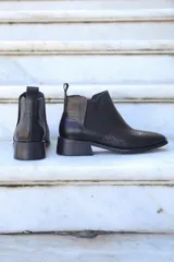 Bota corta de cuero negro con elástico lateral, punta fina y taco bajo.