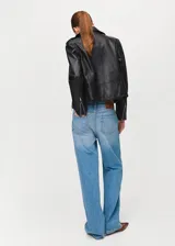Chaqueta estilo biker de cuero negro, con cuello de solapa con muescas, cierre frontal cruzado con cremallera, bolsillos laterales con cremallera y un bolsillo pequeño con solapa y broche a presión.