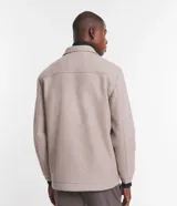 Campera pesada tipo trucker de polivelour color beige, con cuello camisero, cierre frontal por cremallera y dos bolsillos frontales con solapa en el pecho.