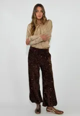 Pantalon de corte recto y tiro alto, confeccionado en tela cubierta de lentejuelas color marrón oscuro con acabado brillante. Posee forro interior y cintura elástica.