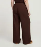 Pantalón de tiro alto, corte flare (acampanado), color marrón oscuro, confeccionado en tejido texturizado anarruga con cintura elástica.