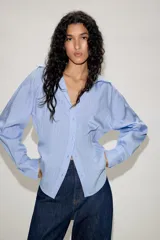 Camisa de manga larga con cuello solapa y escote en pico. Presenta un diseño entallado en la cintura y cierre frontal mediante botones.